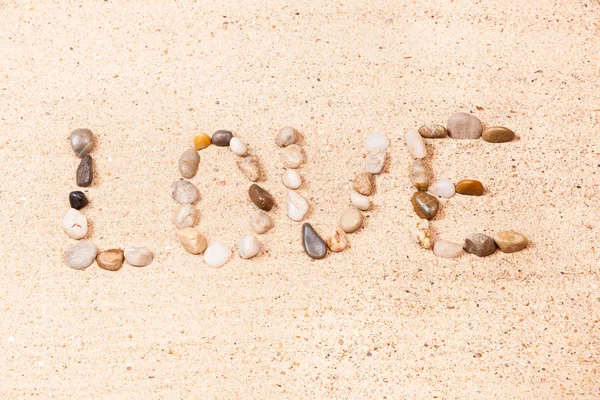 ビーチの砂の小石で書かれた単語の愛 — ストック写真