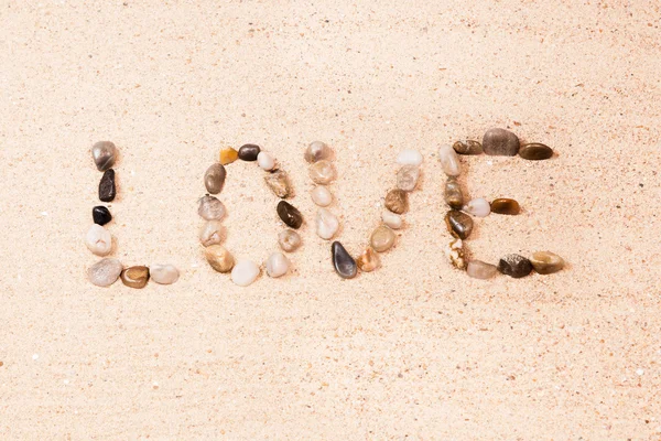 Parola d'amore scritta con ciottoli sulla sabbia — Foto Stock