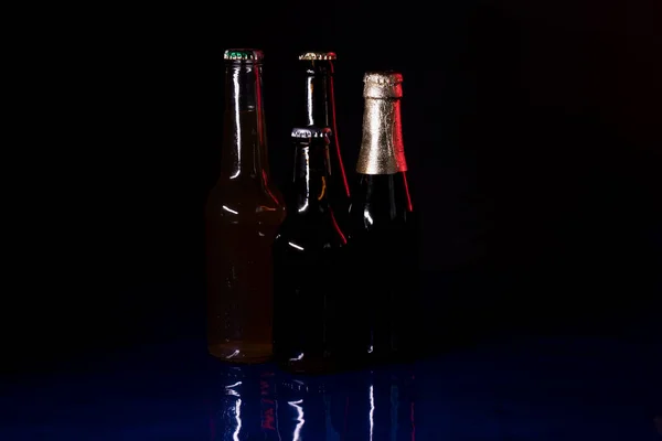 Négy Sörösüveg Sziluettje Fekete Alapon Kék Fényes Felületen — Stock Fotó