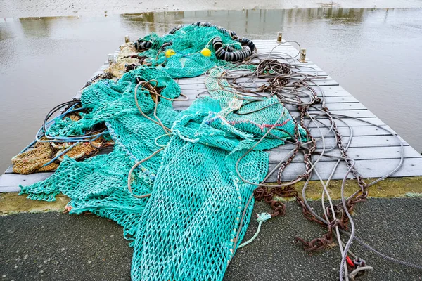 blue fishing net on a pontoon with its ropes and floats covered with morning frost