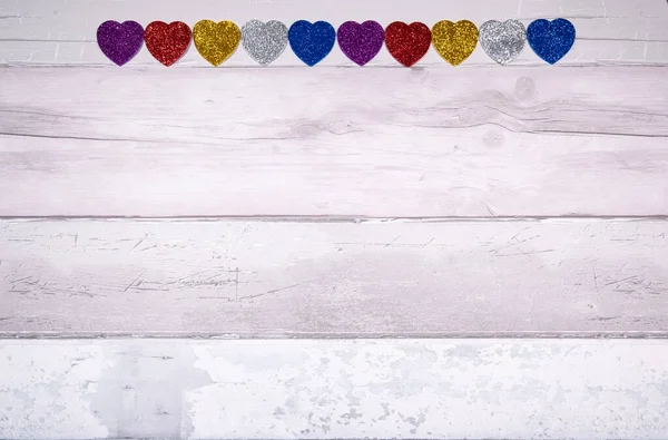 古い寄木細工の床のような古い木製の板の背景にすべての色の輝きを持つ心 バレンタインデーの概念と一般的に愛 — ストック写真
