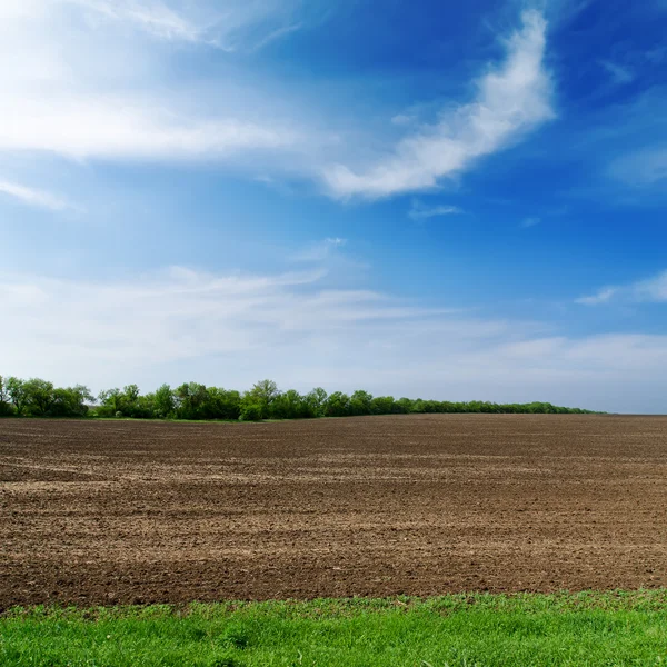 Black spring field and cloudy sky — Stock Photo, Image