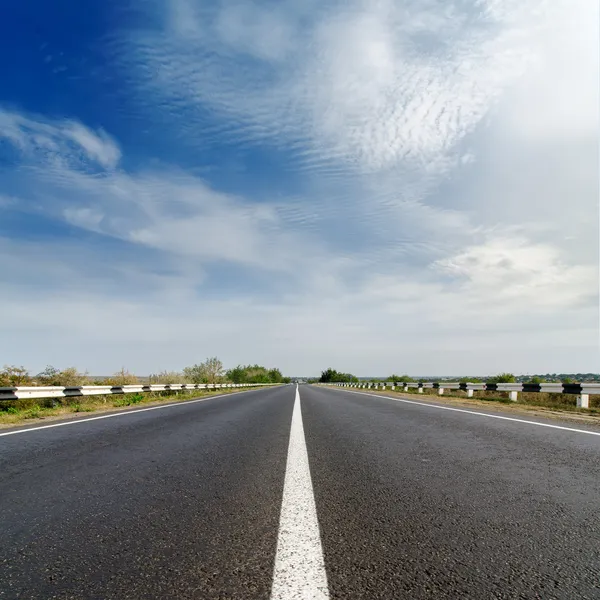 Closeup camino bajo el nublado cielo azul — Foto de Stock