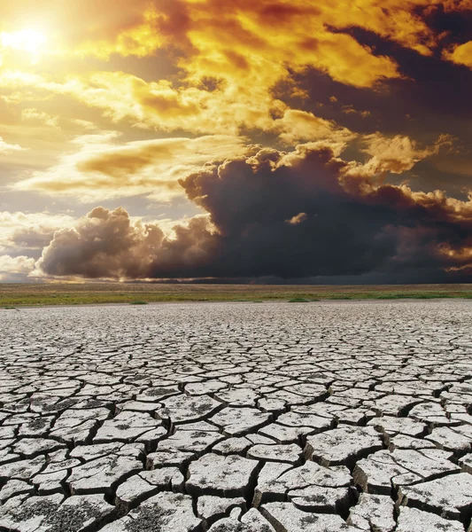 Dramatische zonsondergang over droge gebarsten aarde — Stockfoto