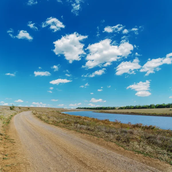 Schmutzige Landstraße in der Nähe von Fluss und blauem Himmel — Stockfoto