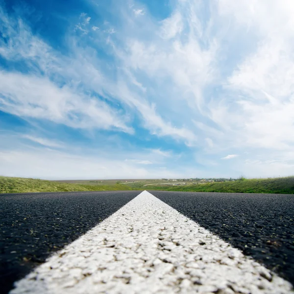 Witte lijn op asfaltweg dicht omhoog en bewolkte hemel — Stockfoto