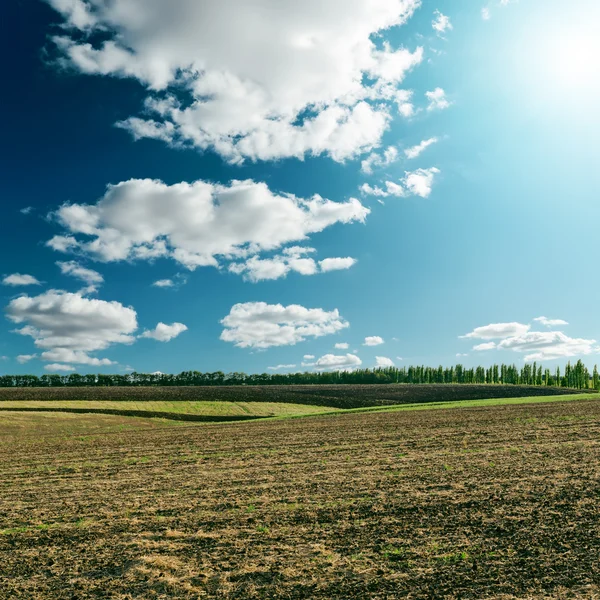 Cloudy sky with sun over field — Stock Photo, Image