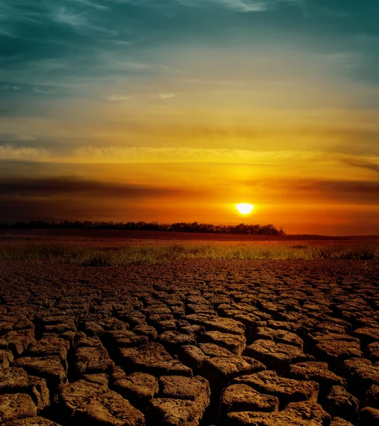 Espectacular puesta de sol sobre la tierra agrietada — Foto de Stock