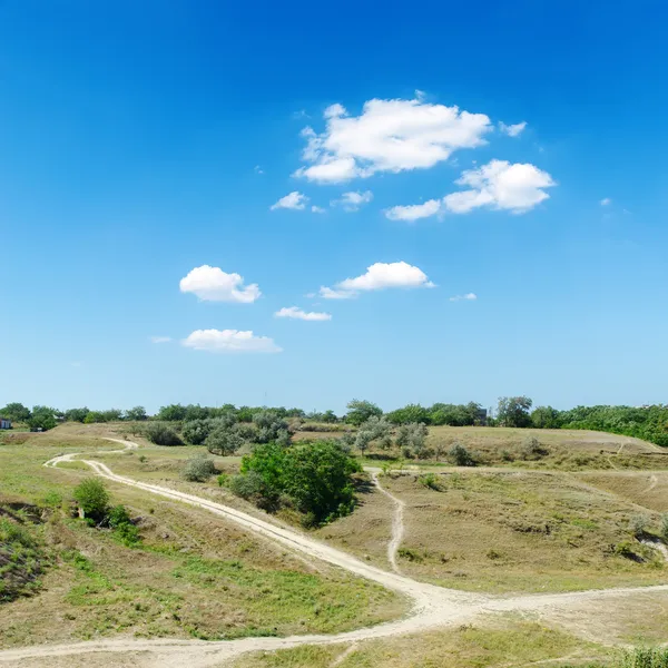 Hill to river with trails under blue sky with clouds — Stock Photo, Image