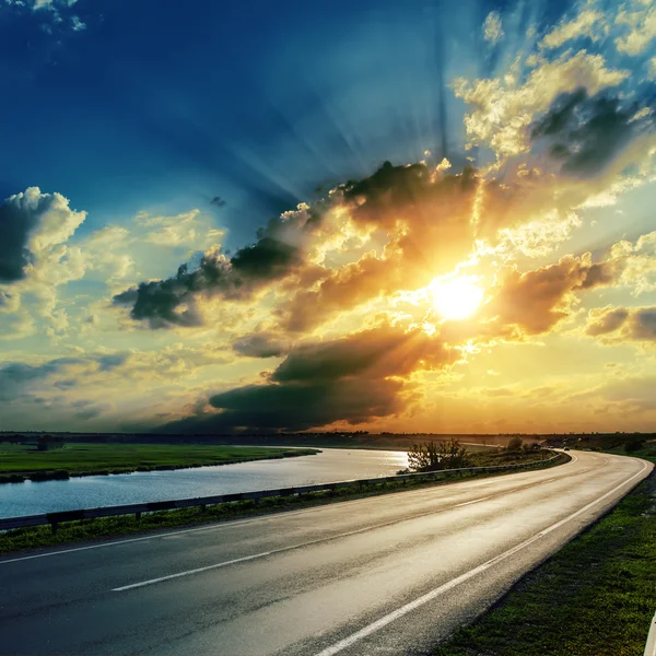 Zonsondergang over asfaltweg en rivier — Stockfoto