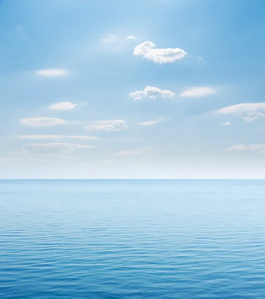 Голубое море и облачное небо над ним — стоковое фото