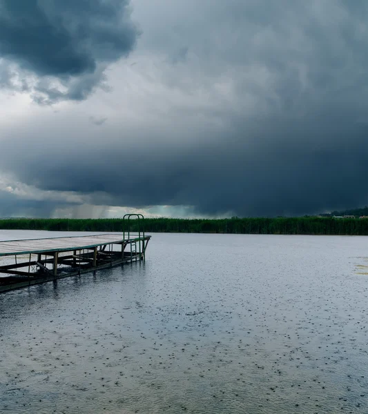 Droppar av regn på floden under mörka moln — Stockfoto