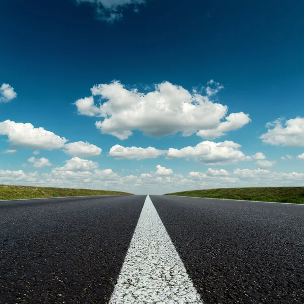 Асфальтовая дорога к горизонту в глубокое синее небо облачно — стоковое фото