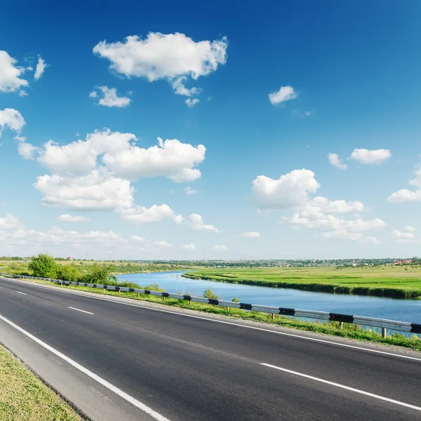 Aspalt road, w pobliżu rzeki w pochmurne niebo — Zdjęcie stockowe