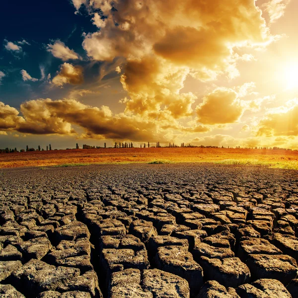 Oranje zon in wolken boven gebarsten aarde — Stockfoto