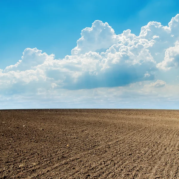 Geploegd veld in het voorjaar en wolken boven het — Stockfoto