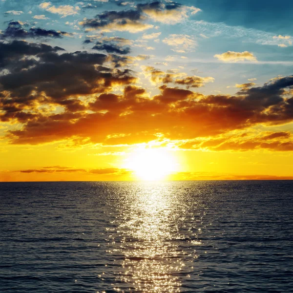 Puesta de sol naranja sobre agua oscura — Foto de Stock