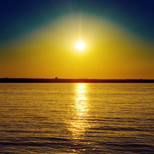 Oranje zonsondergang over het donkere water — Stockfoto