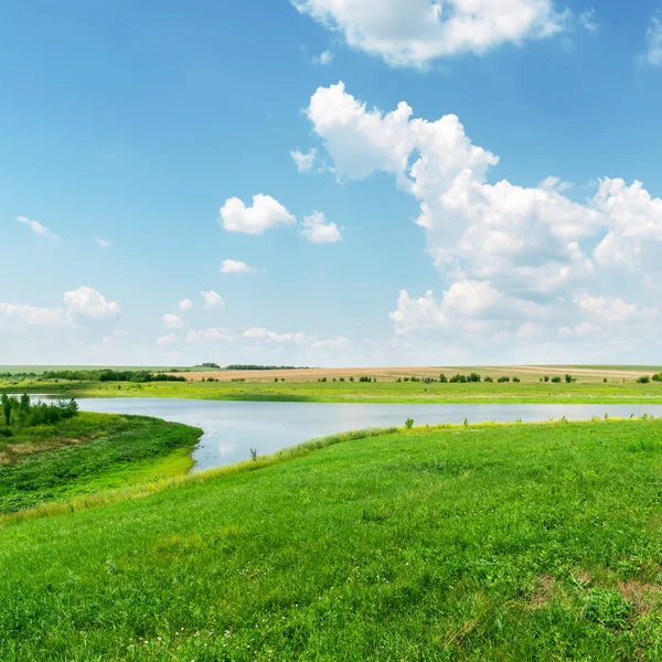 Groen gras, de rivier en de wolken in blauwe hemel — Stockfoto