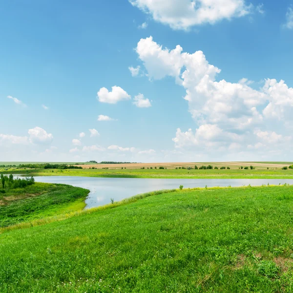 Grünes Gras, Fluss und Wolken am blauen Himmel — Stockfoto