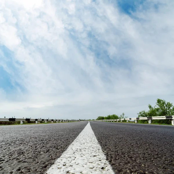 White line on asphalt road and clouds over it — Stock Photo, Image