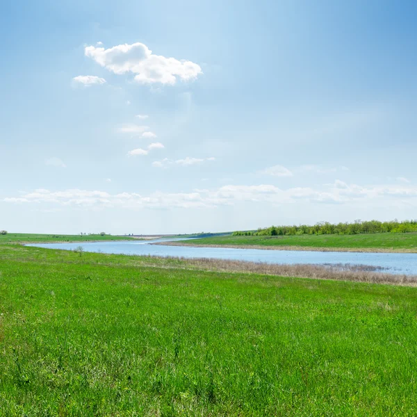 En río verde hierba y las nubes sobre él — Zdjęcie stockowe