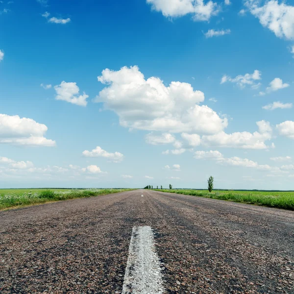 Асфальтована дорога крупним планом під хмарами в блакитному небі — стокове фото
