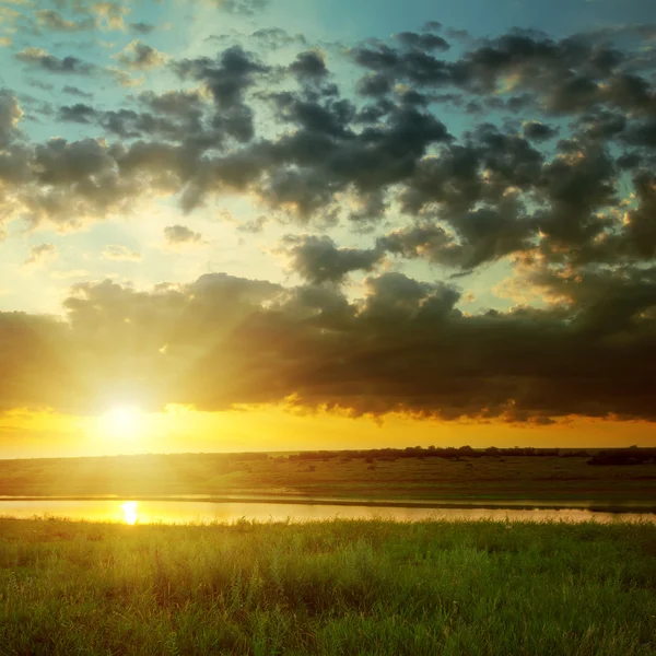 Puesta de sol naranja con nubes oscuras sobre el río —  Fotos de Stock