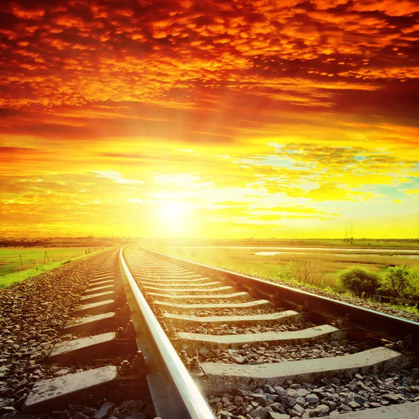 Sunset with red clouds and railroad to horizon — Stock Photo, Image