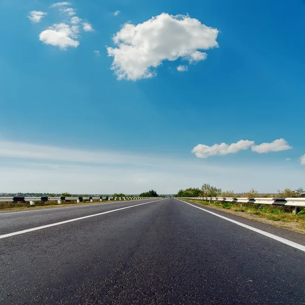 Asfaltweg tot horizon onder blauw bewolkte hemel — Stockfoto