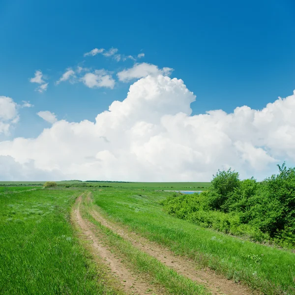 Sucio camino en verde paisaje y nubes sobre él — Foto de Stock