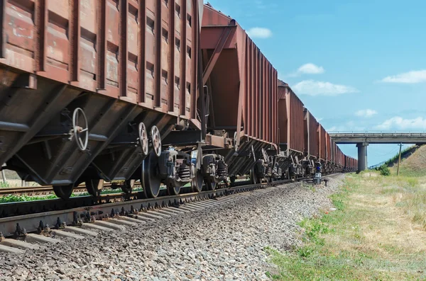 Vagones de un tren de mercancías en movimiento van al horizonte bajo el puente — Foto de Stock