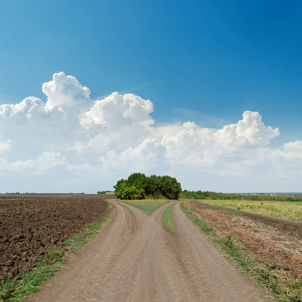 Duas estradas rurais para o horizonte e nuvens no céu azul — Fotografia de Stock