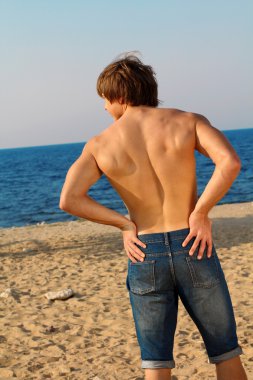 yakışıklı kaslı adam sahilde Jeans dinleniyor.