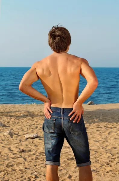 Fit Man in jeans looking away on ocean — Stock Photo, Image