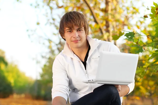 Giovane con computer portatile nel parco, fuori stagione — Foto Stock