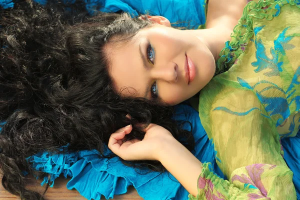 Young brunette woman lying on fabric drapery — Stockfoto