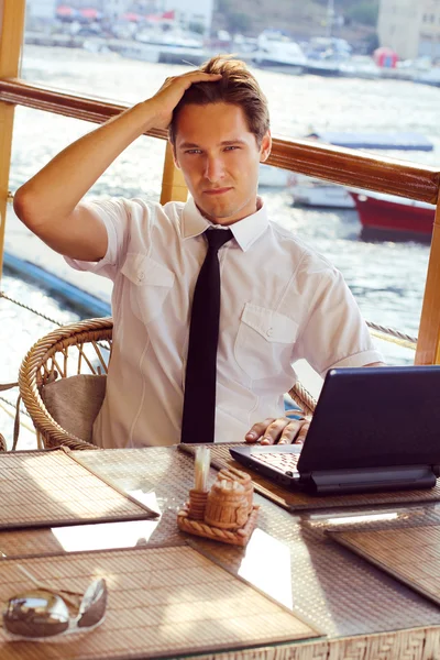 Gutaussehender junger Mann entspannt im Restaurant, sitzt mit Lapto — Stockfoto
