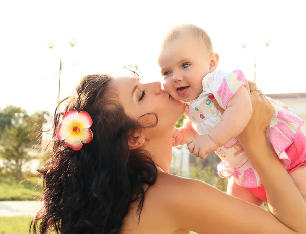 Счастливая мать целует ребенка, на открытом воздухе портрет — стоковое фото