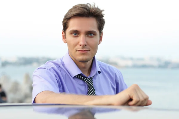 Élégant jeune homme beau sur fond de voiture — Photo