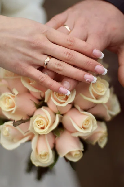 Snubní prsteny a ruce na svatební kytice — Stock fotografie