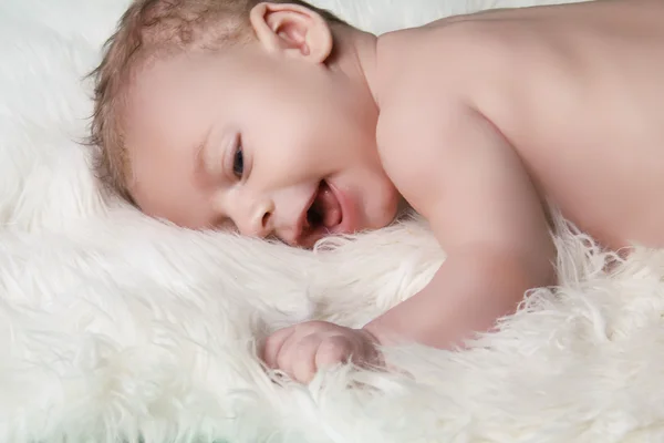Portrait of happy smiling baby boy on white fur coat background — Stock Photo, Image