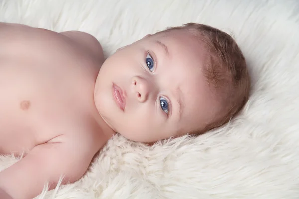 Zoek baby liggend op bont witte bed — Stockfoto