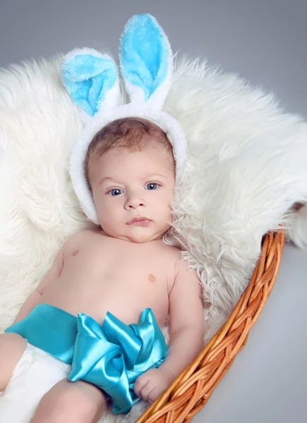 Portrait of baby boy with bow on white fur coat in basket — Stock Photo, Image