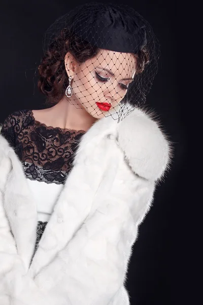 Elegante mujer con abrigo de piel blanca aislado sobre fondo negro — Foto de Stock