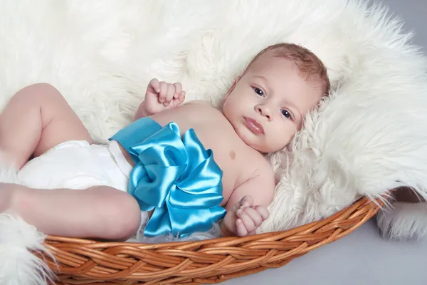 Portrait of Newborn baby lying on fur with blue bow in bed — Stock Photo, Image