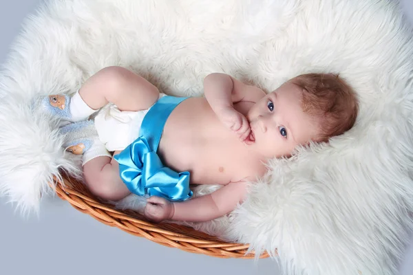 Portrait of Newborn baby lying on fur with blue bow in bed — Stock Photo, Image