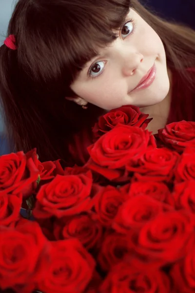 Ευτυχής χαμογελαστοί μικρό κορίτσι με τα κόκκινα τριαντάφυλλα μπουκέτο λουλούδια — Φωτογραφία Αρχείου