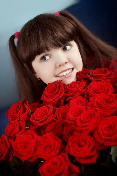Feliz niña sonriente con flores de ramo de rosas rojas — Foto de Stock