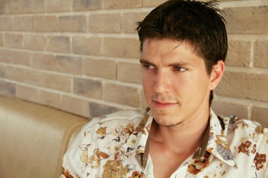 zarif genç yakışıklı adam uzakta tuğla duvar arka plan üzerinde seyir